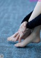 A woman sitting on the floor with her hands on her feet.