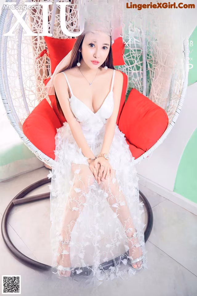 A woman in a white dress sitting on a red chair.