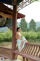 A naked woman sitting on a bench in a park.