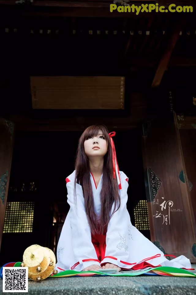 A woman in a white and red dress sitting on the ground.