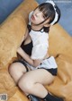 A woman in a maid outfit is sitting on a couch.