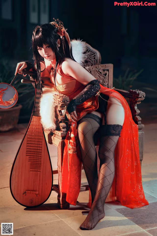 A woman in a red dress sitting on a chair holding a mandolin.