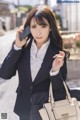 A woman in a business suit talking on a cell phone.