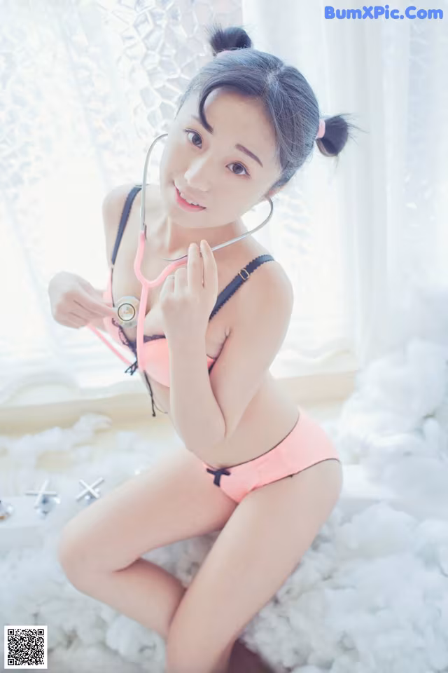 A woman in a pink bikini with a stethoscope on her neck.