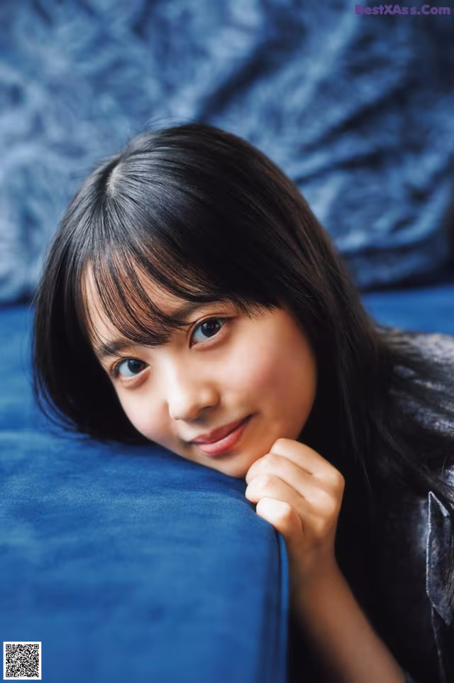 A young woman leaning on a blue couch.