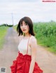 A woman in a red dress standing on a dirt road.