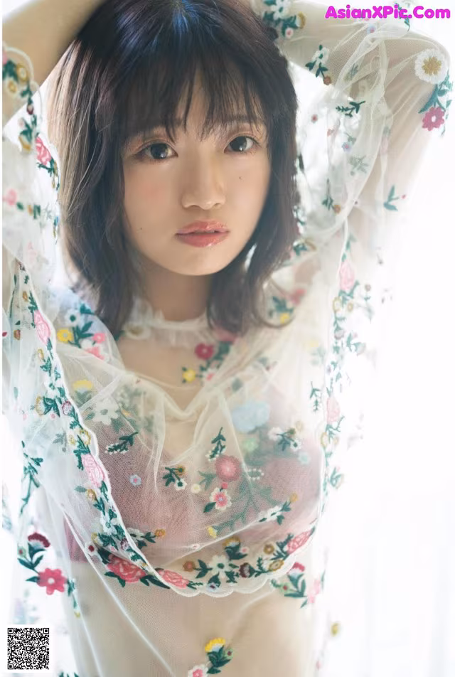 A woman in a sheer white dress with flowers on it.