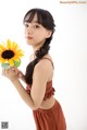 A young woman holding a sunflower in her hand.