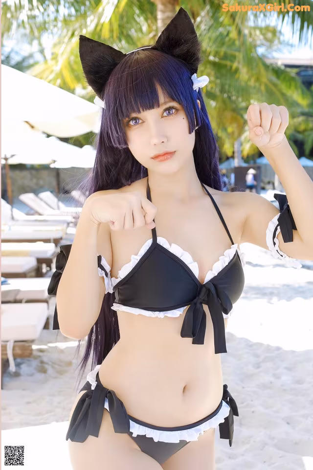 A woman in a black and white bikini posing on a beach.