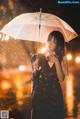 A woman standing in the rain holding an umbrella.