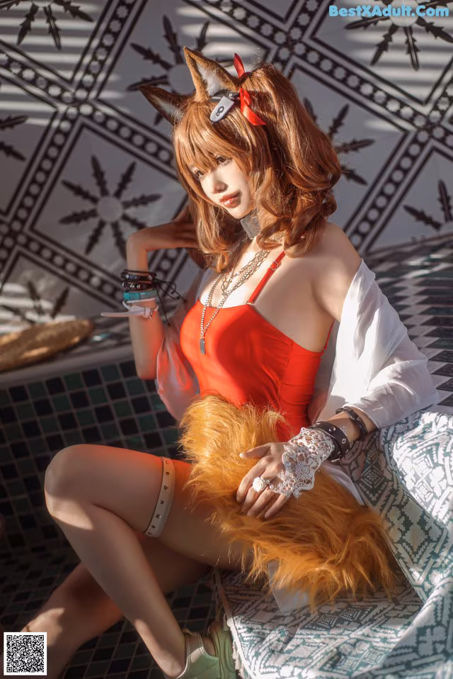 A woman in a red dress sitting on a couch.