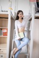 A woman sitting on top of a bunk bed holding a book.