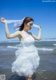 A woman in a wedding dress standing in the ocean.