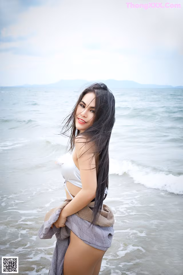 A woman in a white bikini standing in the ocean.