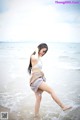 A woman in a white bikini standing in the ocean.