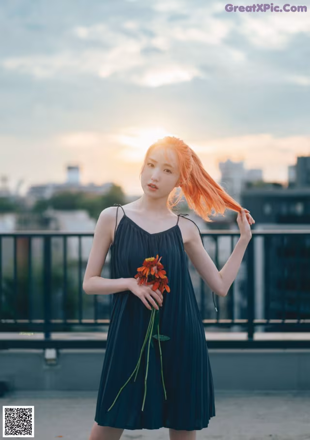 A woman in a black dress holding a flower.